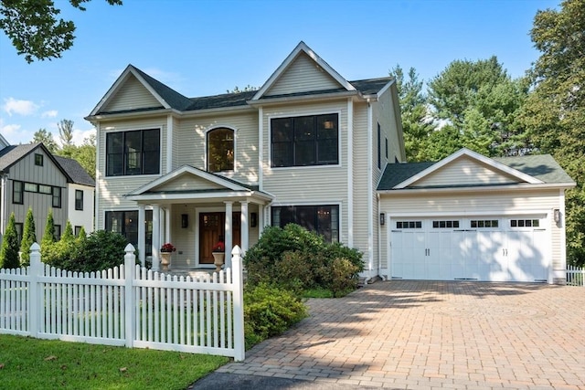 view of front of property featuring a fenced front yard, decorative driveway, and an attached garage