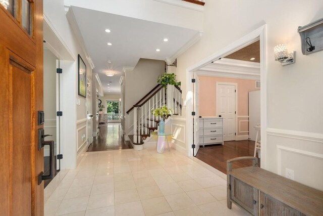 entryway with light hardwood / wood-style flooring, a tray ceiling, and ornamental molding