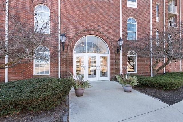 view of exterior entry featuring brick siding and french doors