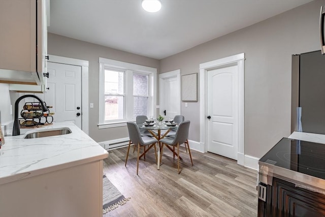 dining area with sink, a baseboard heating unit, and light hardwood / wood-style floors