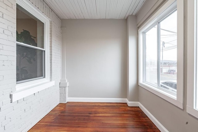 empty room with brick wall and dark wood-type flooring