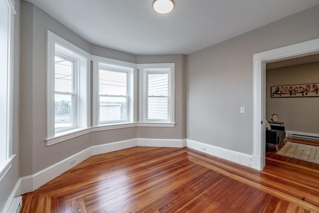 empty room featuring a baseboard radiator and hardwood / wood-style flooring