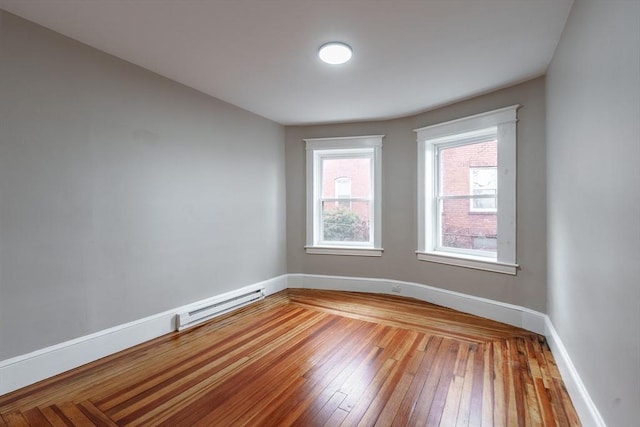 unfurnished room with wood-type flooring and a baseboard heating unit