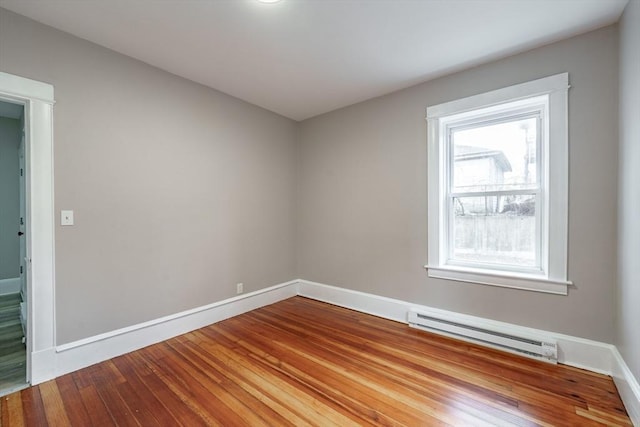 unfurnished room featuring baseboard heating, hardwood / wood-style flooring, and plenty of natural light