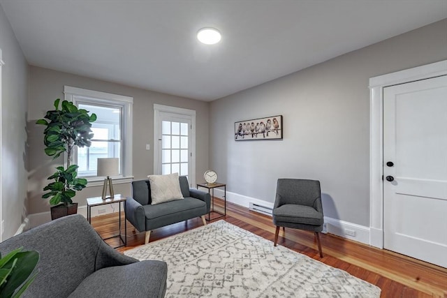 living area with a baseboard heating unit and wood-type flooring