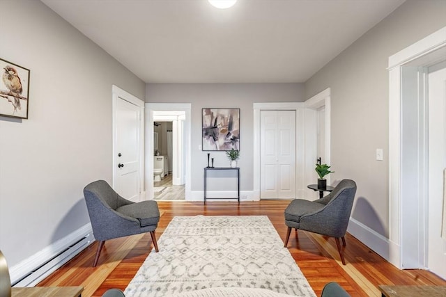 living area featuring baseboard heating and wood-type flooring