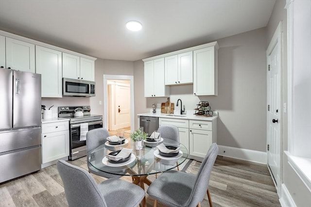 kitchen with sink, white cabinets, light hardwood / wood-style floors, and stainless steel appliances