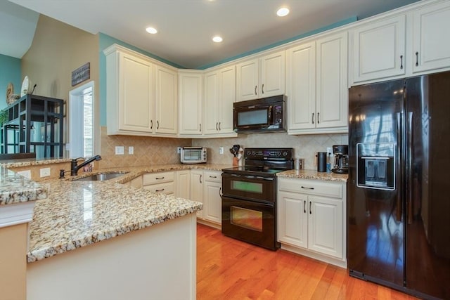 15 Herrick Dr Unit 15, Methuen, MA 01844 - kitchen featuring black appliances, a peninsula, a sink, light stone countertops, and light wood-style flooring