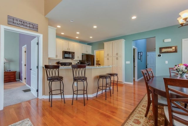 15 Herrick Dr Unit 15, Methuen, MA 01844 - kitchen with black appliances, a peninsula, light wood-style flooring, a kitchen bar, and recessed lighting