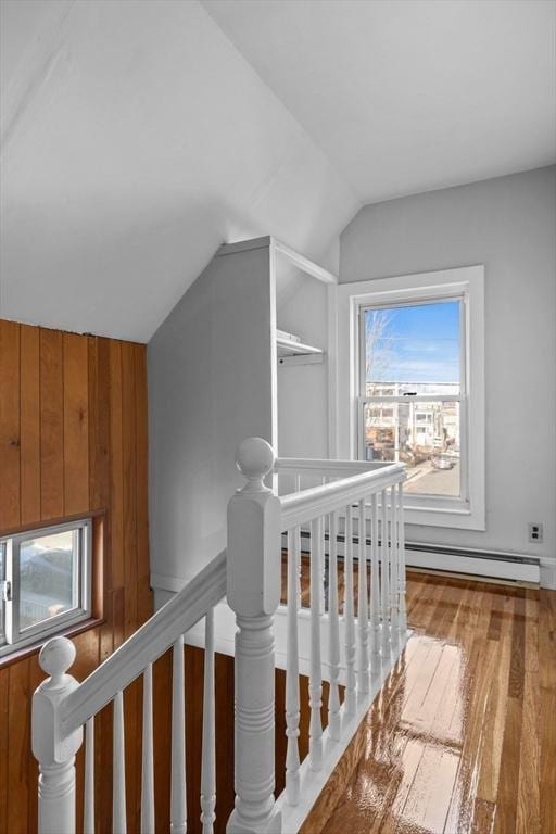 stairway with lofted ceiling, wooden walls, and wood finished floors