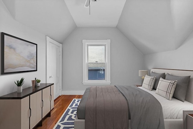 bedroom with baseboards, dark wood-style flooring, and vaulted ceiling