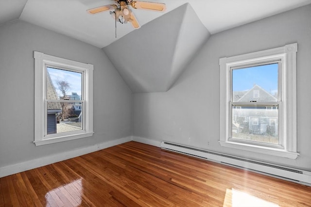 additional living space with baseboards, lofted ceiling, hardwood / wood-style floors, baseboard heating, and a ceiling fan