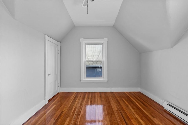 additional living space with a baseboard heating unit, hardwood / wood-style flooring, baseboards, and lofted ceiling