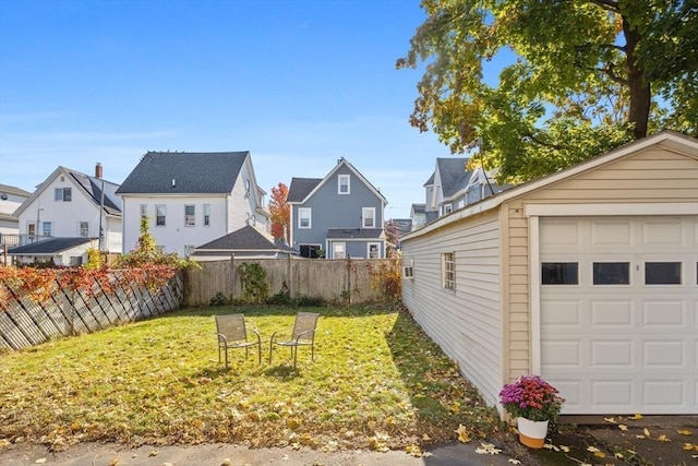 view of yard with a garage, a residential view, an outdoor structure, and fence