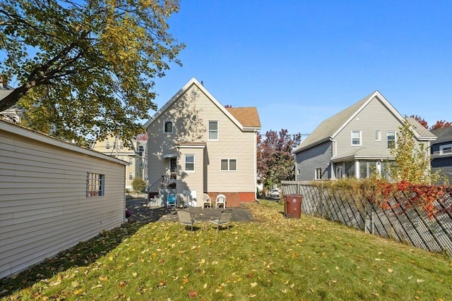 rear view of house featuring a yard and fence