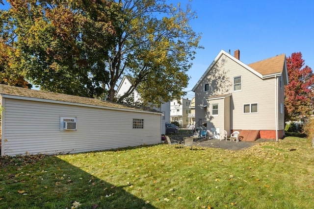 back of house featuring an outbuilding, cooling unit, a chimney, and a yard