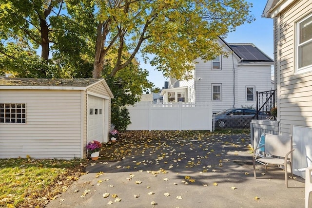 view of patio with a detached garage, an outdoor structure, and fence