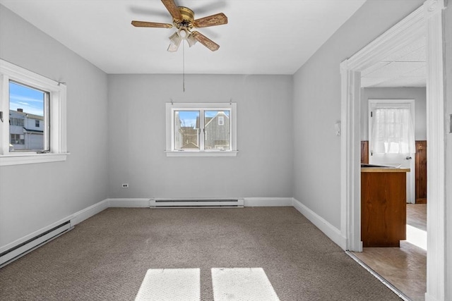 carpeted spare room featuring a wealth of natural light, baseboards, and baseboard heating