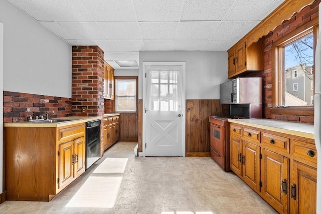 kitchen featuring wooden walls, a wainscoted wall, dishwasher, light countertops, and electric range oven