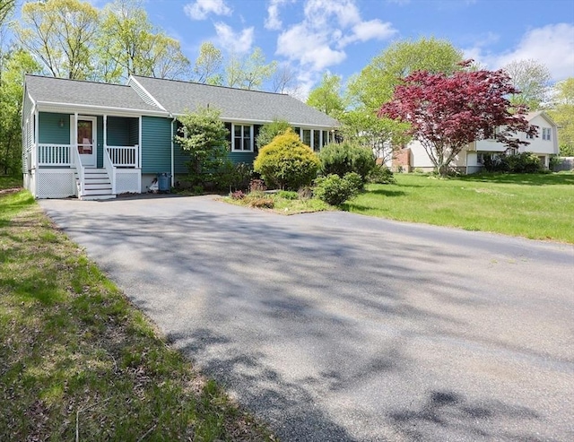 view of front of home with a porch, a front yard, and driveway