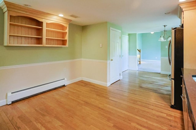 spare room featuring a baseboard heating unit, light wood-type flooring, baseboards, and recessed lighting