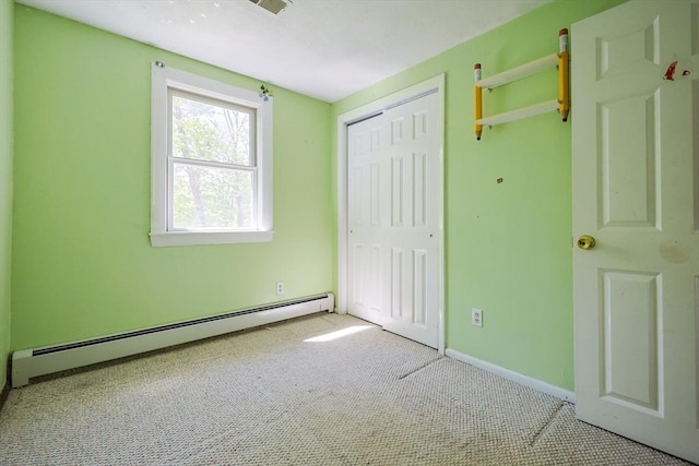 unfurnished bedroom featuring baseboard heating, carpet flooring, a closet, and baseboards