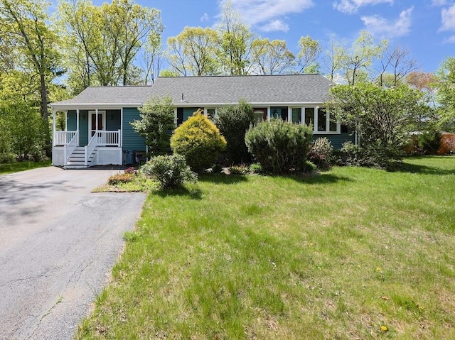single story home featuring a porch, a front lawn, and driveway