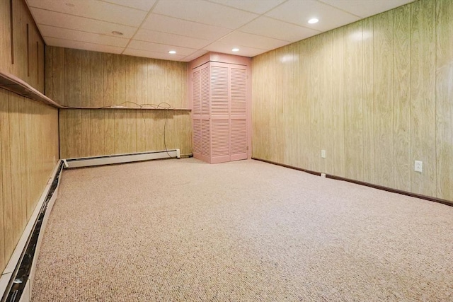 finished basement with a baseboard heating unit, carpet flooring, wooden walls, and recessed lighting