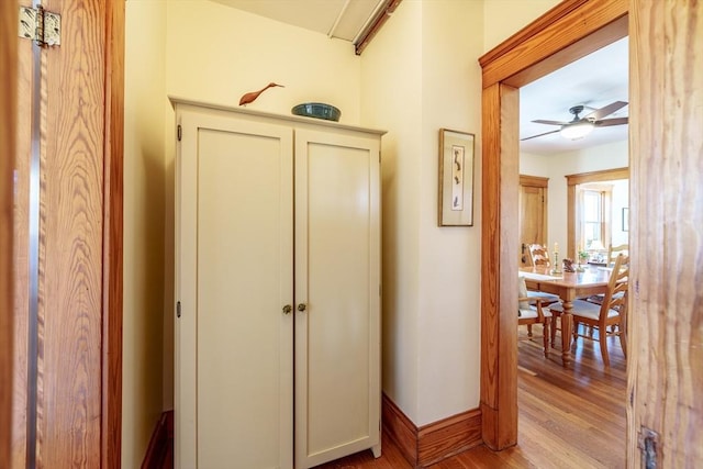 hall with light wood-type flooring and baseboards