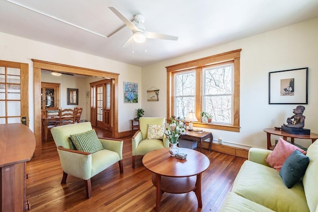 living room featuring a ceiling fan, baseboards, and wood finished floors