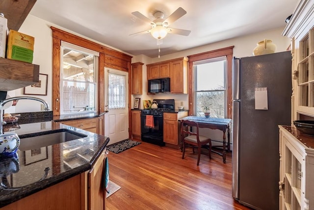 kitchen with a healthy amount of sunlight, a sink, black appliances, and wood finished floors