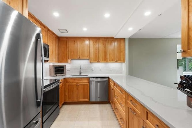 200 Ledgewood Dr Unit 604, Stoneham, MA 02180 - kitchen with stainless steel appliances, decorative backsplash, recessed lighting, light stone countertops, and brown cabinets