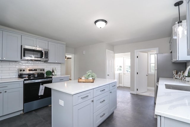 7 Dewey Ave, East Longmeadow, MA 01028 - kitchen with appliances with stainless steel finishes, decorative backsplash, gray cabinetry, and a kitchen island