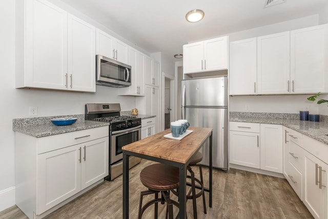 kitchen with light stone counters, appliances with stainless steel finishes, and white cabinetry