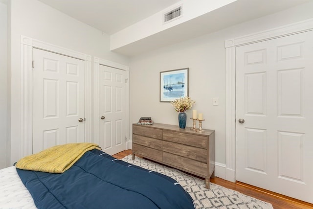 bedroom featuring two closets and hardwood / wood-style floors