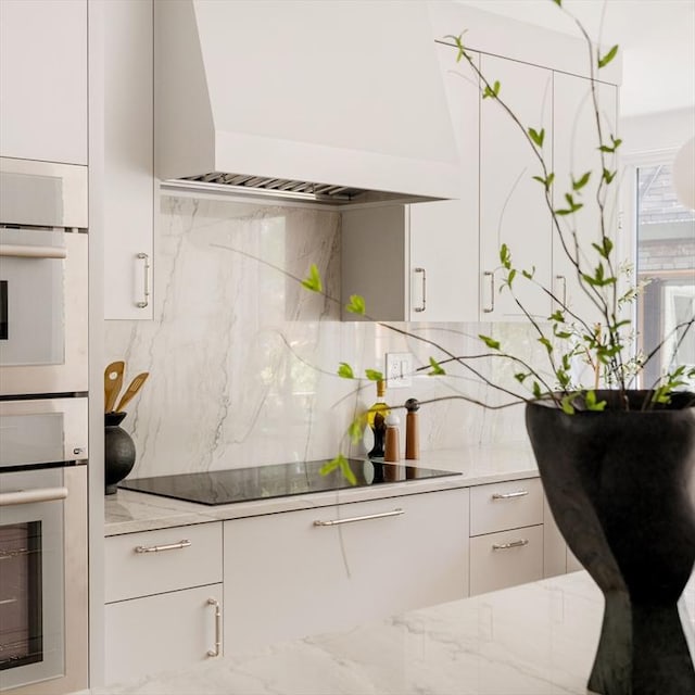 13 Mellen St, Cambridge, MA 02138 - kitchen featuring custom exhaust hood, backsplash, white cabinetry, and light stone countertops