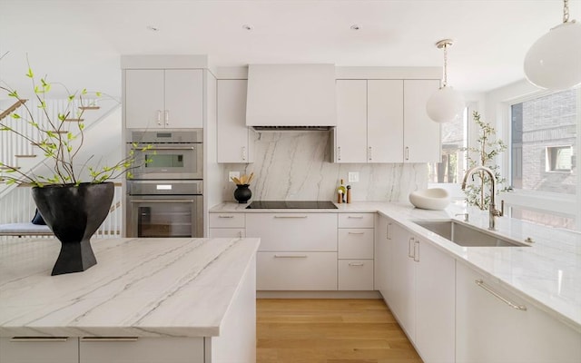 13 Mellen St, Cambridge, MA 02138 - kitchen with a sink, double oven, black electric cooktop, decorative backsplash, and light wood-type flooring