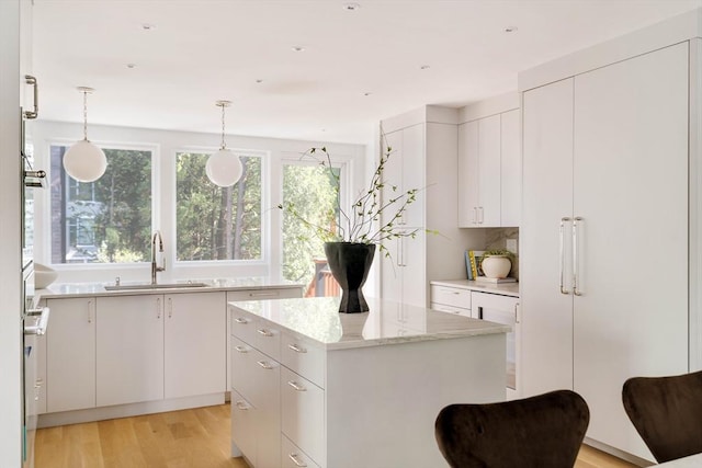 13 Mellen St, Cambridge, MA 02138 - kitchen featuring a sink, a kitchen island, light wood finished floors, white cabinets, and hanging light fixtures