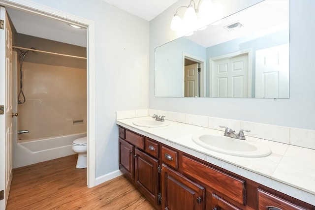 bathroom with toilet, visible vents, a sink, and wood finished floors