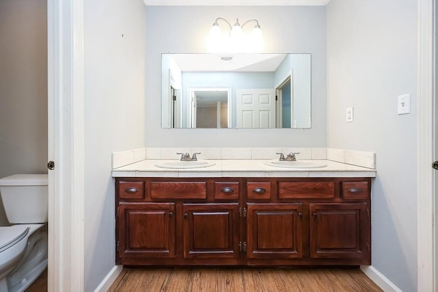 bathroom with toilet, a sink, and wood finished floors