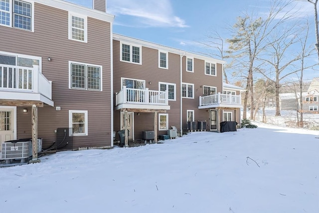 snow covered back of property featuring a chimney and cooling unit