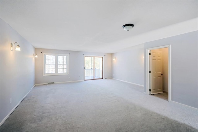 spare room featuring visible vents, baseboards, and light colored carpet