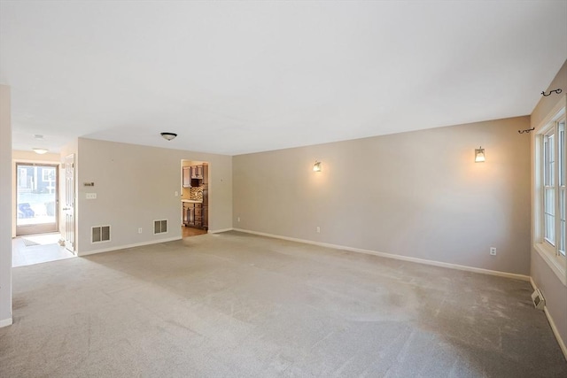 spare room with light colored carpet, visible vents, plenty of natural light, and baseboards