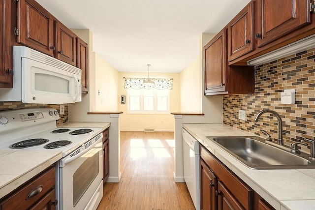 kitchen featuring light countertops, white appliances, a sink, and decorative light fixtures