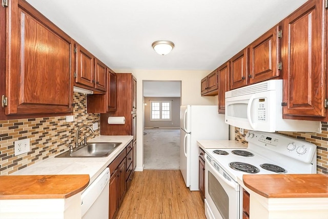 kitchen featuring white appliances, a sink, baseboards, light countertops, and decorative backsplash