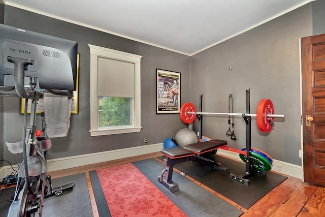 workout area featuring wood finished floors, crown molding, and baseboards