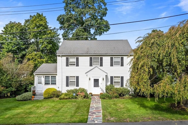 colonial inspired home with a front yard and a shingled roof