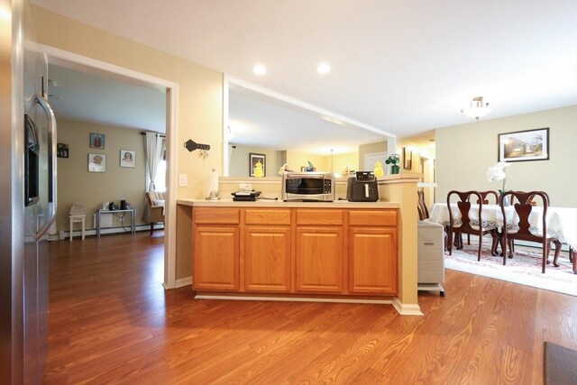 4 Colonial Rd, Webster, MA 01570 - kitchen with a baseboard heating unit, a peninsula, stainless steel appliances, light wood-style floors, and light countertops