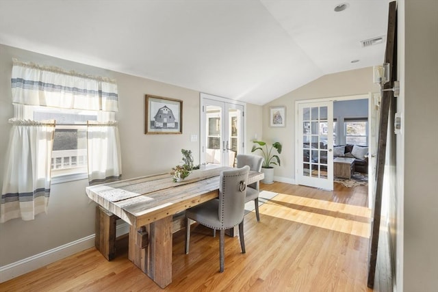 dining area with french doors, light hardwood / wood-style floors, and vaulted ceiling