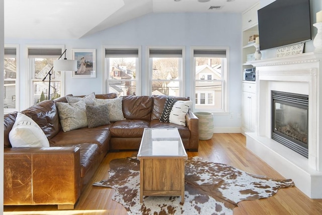 living room featuring light hardwood / wood-style floors, lofted ceiling, and a wealth of natural light